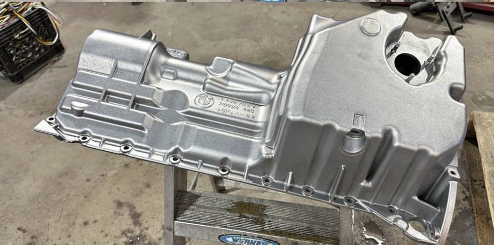 Same oil pan after vapor honing, clean satin aluminum