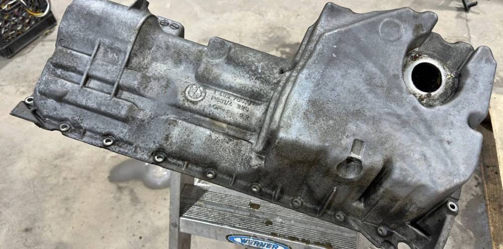 Oil pan before vapor honing, stained with oil and corrosion